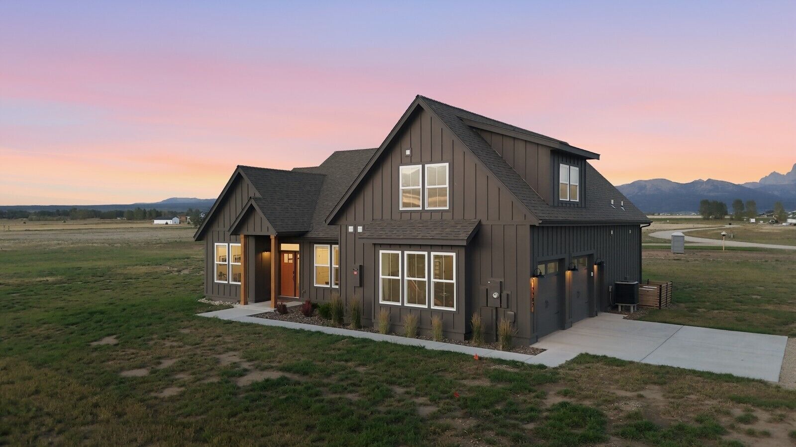 A modern two-story house with a large front porch, a garage, and a well-maintained lawn.