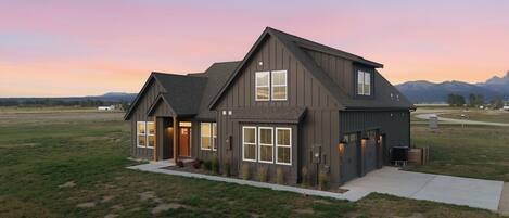 A modern two-story house with a large front porch, a garage, and a well-maintained lawn.
