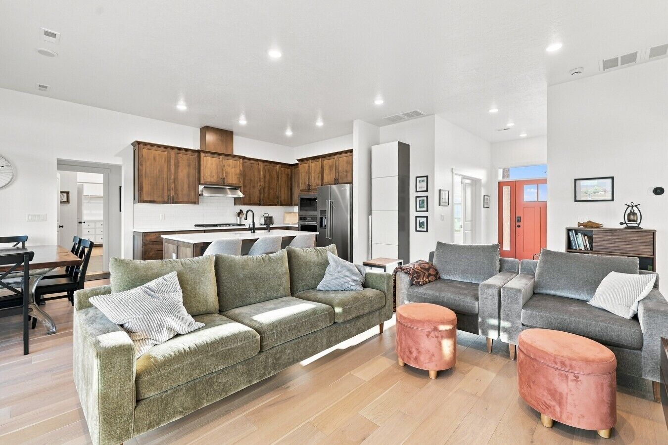 Un salon moderne comprenant un canapé, un pouf et un coin repas avec des chaises et une table.