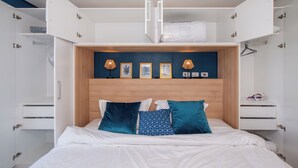 A bedroom with a bed, two bedside tables, a wardrobe, and a headboard with wall art and lamps. - Corporate Stays First Living - 806 (Asunción)
