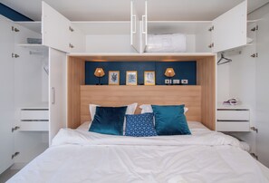 A bedroom with a bed, two bedside tables, a wardrobe, and a headboard with wall art and lamps. - Corporate Stays First Living - 806 (Asunción)