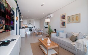 A modern living room with a sofa, coffee table, and a dining area with chairs and a table. - Corporate Stays First Living - 806 (Asunción)