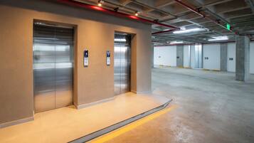 A clean, modern elevator area with a metallic elevator and a wall-mounted control panel.