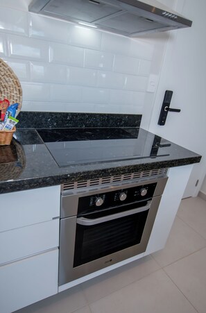 A kitchen with a black countertop, white cabinets, and a stainless steel oven. - Corporate Stays First Living - 806 (Asunción)