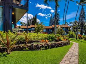 Ein Resort mit gepflastertem Weg, üppiger Bepflanzung und mehrstöckigen Gebäuden mit Balkonen.
