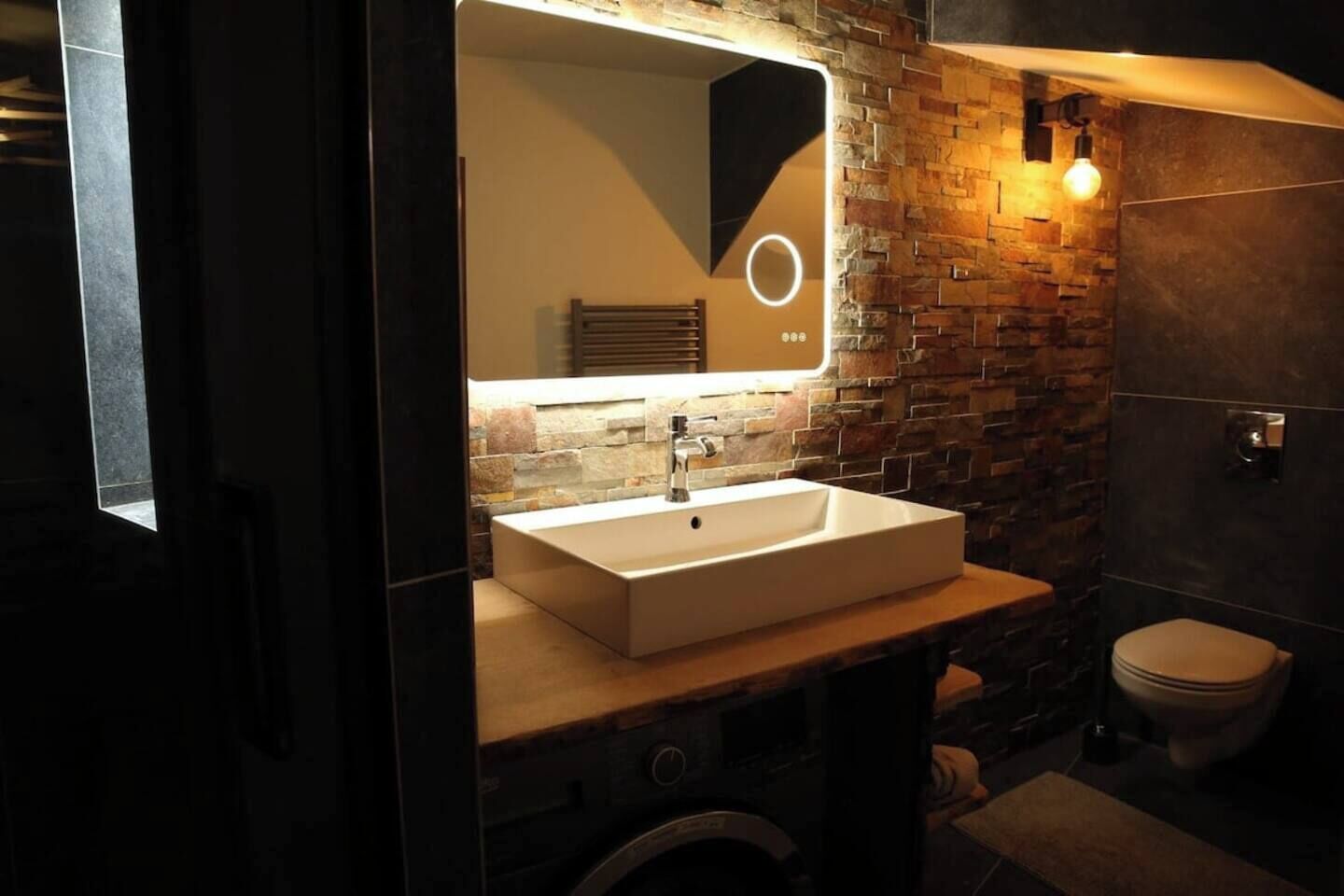 Un baño moderno con un lavamanos rectangular, un espejo y un inodoro.