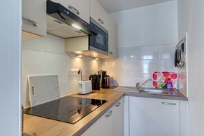 A modern kitchen with a built-in stove, a coffee machine, and a sink. - Le Studio des Peupliers - 30m de la plage (Bray-Dunes)
