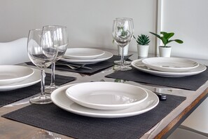 A dining table set with plates, glasses, and cutlery, with small potted plants on the side. - Le Studio des Peupliers - 30m de la plage (Bray-Dunes)