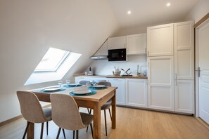 Eine moderne Küche mit weißen Schränken, einer Mikrowelle und einem Essbereich mit Holztisch und Stühlen.
