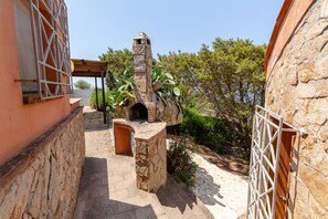 A stone-built outdoor area with a stone oven, a wooden pergola, and a stone wall. - VILLA ALICE with sea view in Torre delle Stelle (TORRE DELLE STELLE)