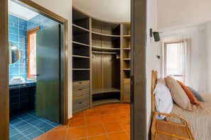Ein Schlafzimmer mit Bett, Nachttisch, Kleiderschrank und einem Badezimmer mit Dusche.