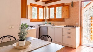 Una cocina con armarios de madera, una estufa y un comedor con mesa y sillas.