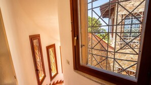 Una escalera conduce a una habitación con un ventanal grande que da a una construcción de piedra.