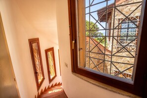 Eine Treppe führt zu einem Raum mit einem großen Fenster, das auf eine Steinstruktur blickt.