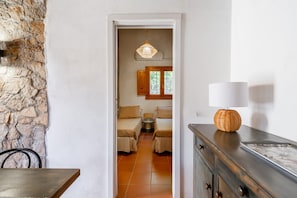 A narrow hallway leading to a room with a stone wall, a wooden cabinet, and a lamp. - VILLA ALICE with sea view in Torre delle Stelle (TORRE DELLE STELLE)