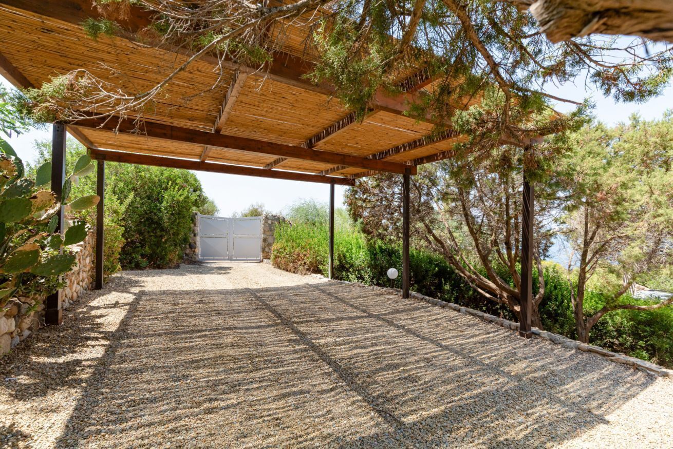 Un espacio al aire libre cubierto con un sendero de grava que conduce a un edificio, rodeado de follaje y árboles.