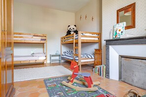 Ein Kinderzimmer mit Etagenbetten, einem Schaukelpferd, einem Bücherregal und einem Kamin.
