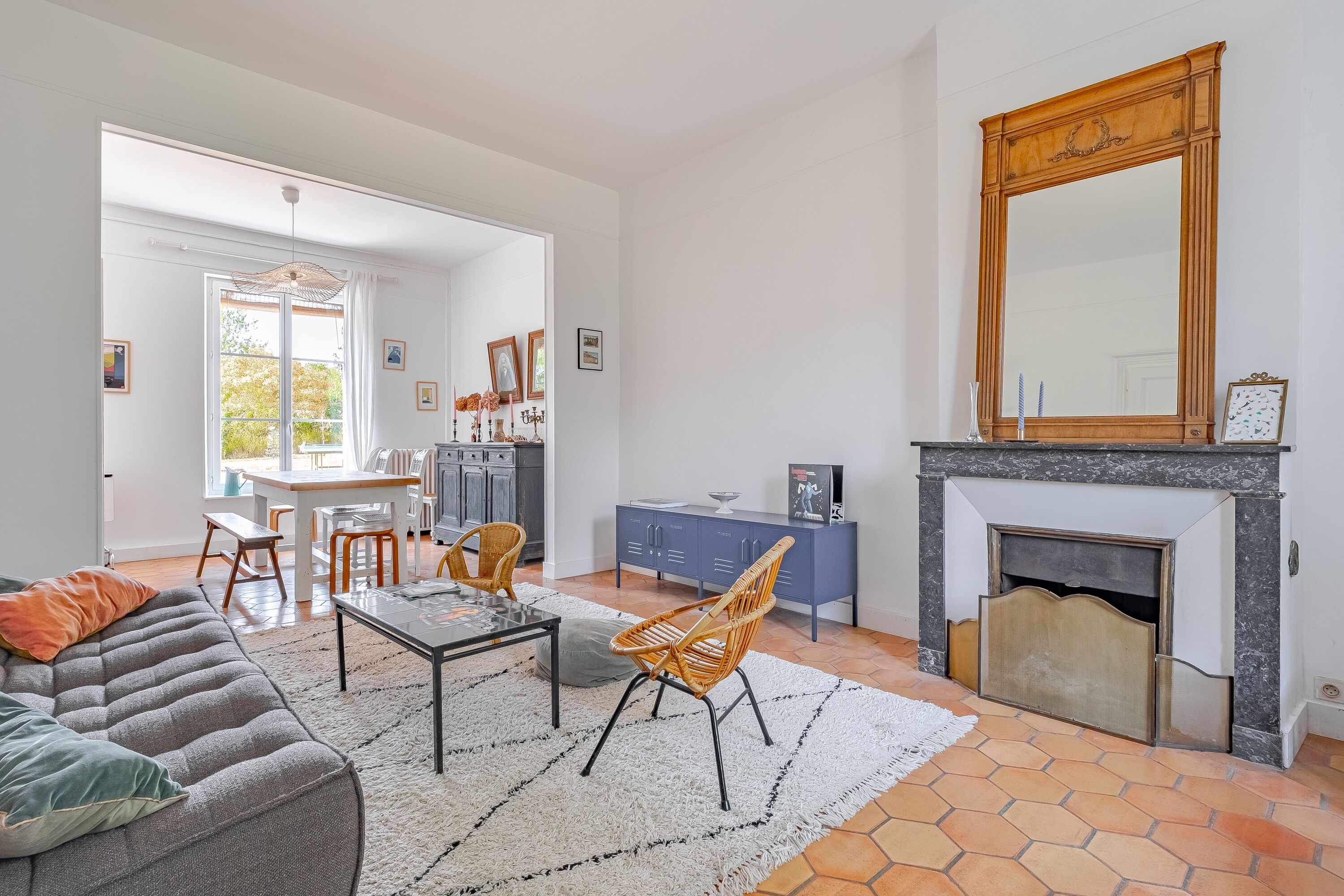 A living room with a sofa, chairs, a coffee table, a fireplace, and a dining area with a table and chairs.