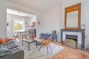 En stue med sofa, lænestole, sofabord, pejs og spiseplads med bord og stole.