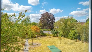 Un jardin avec une table de ping-pong, un chemin de pierres et divers arbres.