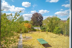 Ein Garten mit Pongtisch, Kiesweg und verschiedenen Bäumen.
