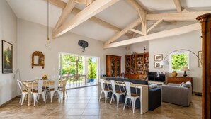 A spacious living area with a dining table, chairs, a sofa, a TV, and a bookshelf. - La Maison Rose - Avec Piscine Privée (Barjac)