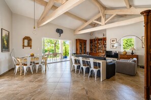 A spacious living area with a dining table, chairs, a sofa, a TV, and a bookshelf. - La Maison Rose - Avec Piscine Privée (Barjac)