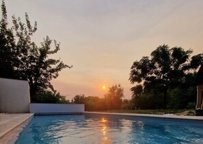 A swimming pool with a sunset in the background. - La Maison Rose - Avec Piscine Privée (Barjac)