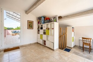A room with a white built-in bookshelf, a wooden chair, and a dining table. - La Maison Rose - Avec Piscine Privée (Barjac)