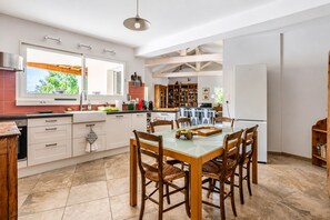Una cocina amplia con comedor, que cuenta con una isla grande, sillas de madera y vistas al exterior.