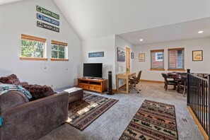 Ein Wohnzimmer mit Fernseher, Kamin und Essbereich mit Tisch und Stühlen.