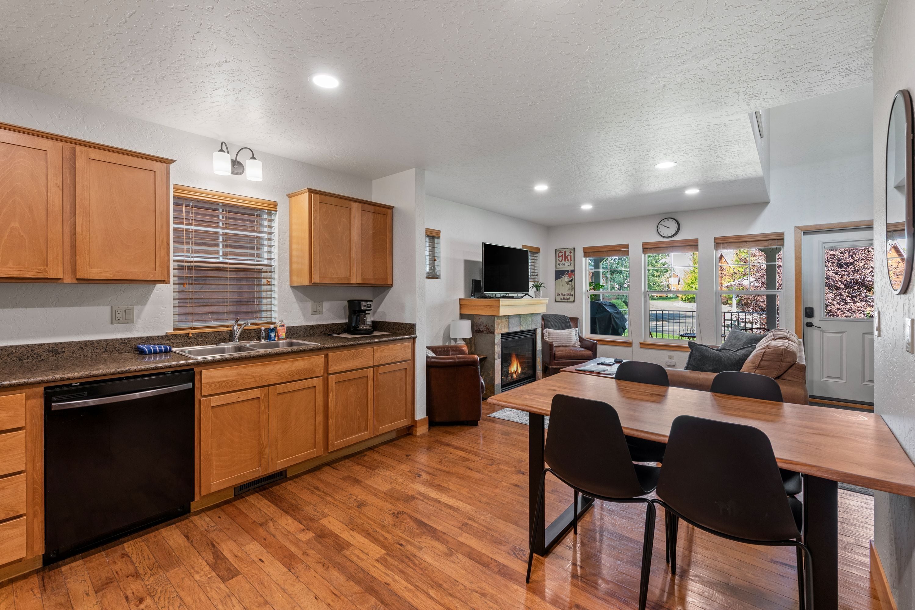 A modern kitchen with wooden cabinets, a built-in dishwasher, and a dining area with a table and chairs.