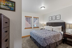 A bedroom with a bed, nightstands, a dresser, and a painting on the wall. - Serenity at Dover Bay | Sleeps 8 (Sandpoint)