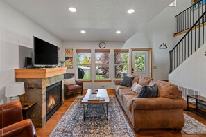 Ein Wohnzimmer mit Kamin, Fernseher, Sofa und Couchtisch.