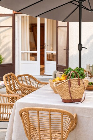 Wicker chairs, a table with a white tablecloth, and a basket with fruits and vegetables. - Maison Sarava – Superior Apartment with Separate Studio & Private Patio (Espira-de-l'Agly)