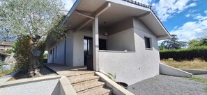 Ein modernes, zweistöckiges Haus mit einer Veranda, einem kleinen Vorgarten und der Hausnummer 27.