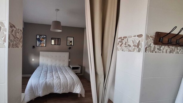 A bedroom with a bed, a nightstand, a hanging lamp, and a wall with a stone pattern. - Villa on the outskirts of Geneva, between the lake and the mountains (Douvaine)