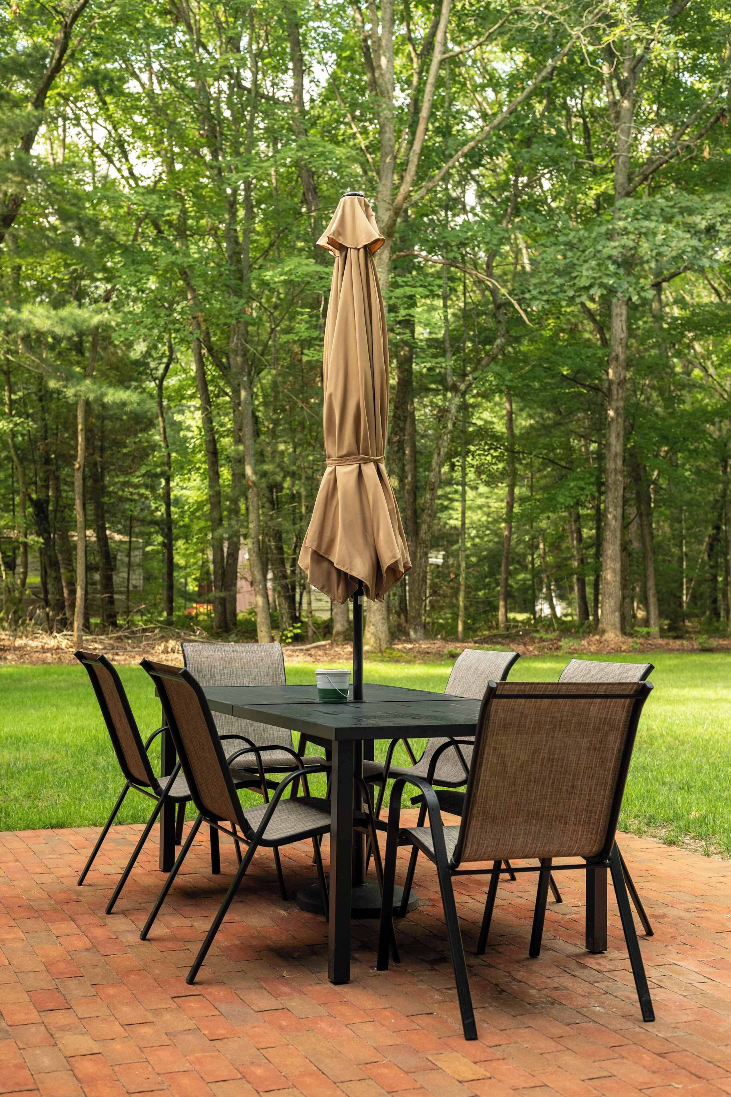 Une table de patio avec un parasol, entourée de chaises.