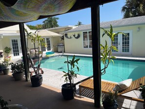 A pool area with a wooden deck, potted plants, and a view of a house with a tiled roof. - Pool - Roomy Historic Home on Beautiful Street Two Houses from the IntraCoastal (Lake Worth Beach)