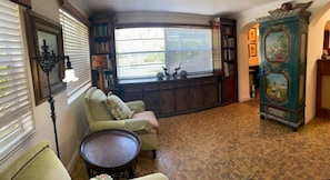 A room with a corner sofa, a small round table, a bookshelf, and a cabinet with artwork. - Pool - Roomy Historic Home on Beautiful Street Two Houses from the IntraCoastal (Lake Worth Beach)