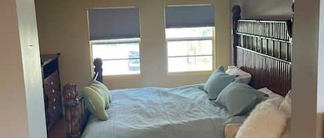 Une chambre à coucher avec un grand lit, une table de chevet, une commode et une fenêtre.