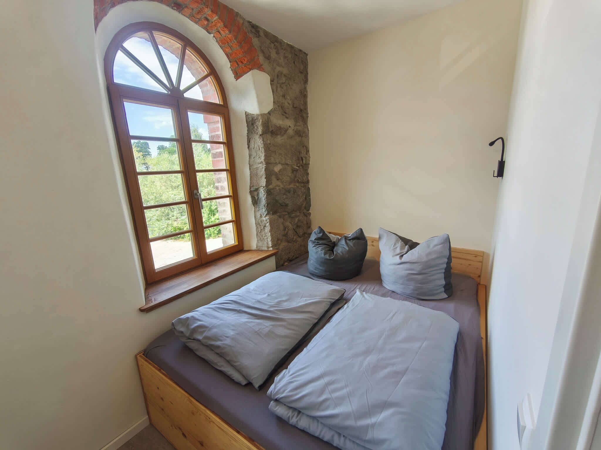 Ein Schlafzimmer mit Fenster, Bett und Steinwand.