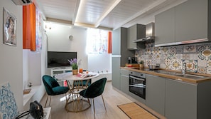 A modern kitchen with a dining area, featuring a TV, a clock, and a colorful backsplash. - Italianway Easy - Angelo della Pergola 7 A (Milan)