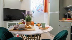 Une cuisine compacte comprenant une table à manger, un téléviseur et une machine à café.