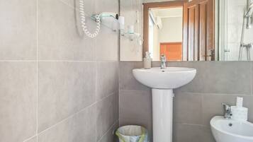 Ein Badezimmer mit einem Standwaschbecken, einem Bidet und einem Spiegel.