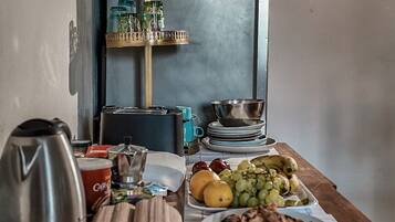 A dining table with plates of food, a kettle, and a coffee machine.