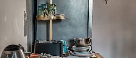 Una mesa de comedor con platos de comida, un hervidor y una cafetera.