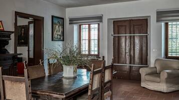 Zona pranzo con tavolo in legno, sedie, una pianta in vaso e un armadietto in legno.