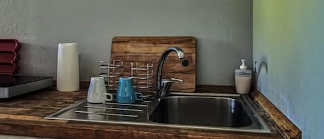 A kitchen with a wooden countertop, stainless steel sink, and a paper towel dispenser.