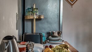 A dining table with a variety of food items, a kettle, and a coffee machine.